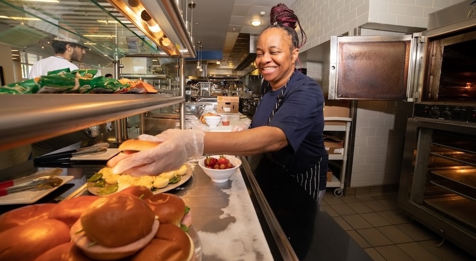 Employee in Dining Services serving food.